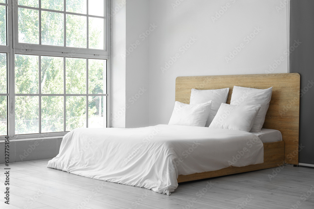 Interior of light bedroom with comfortable double bed and white pillows