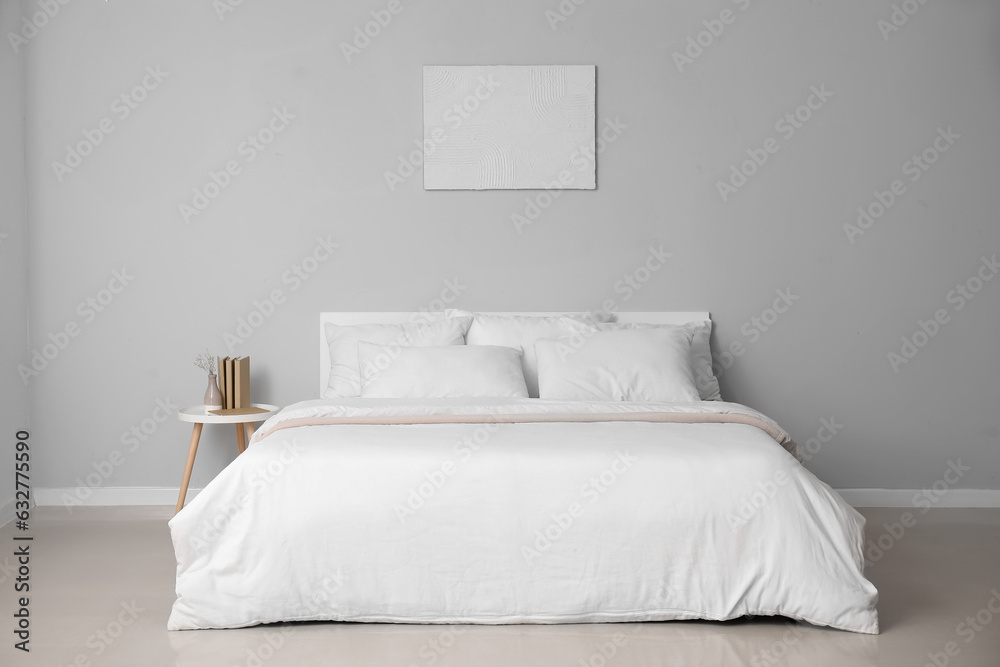 Interior of light bedroom with large double bed and white pillows