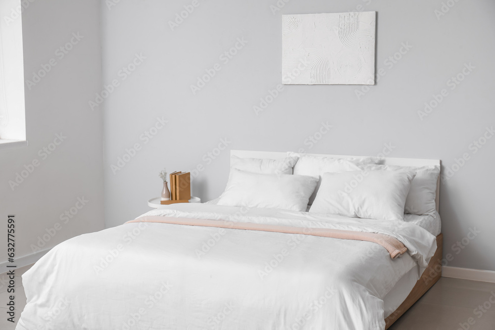 Interior of light bedroom with large double bed and white pillows