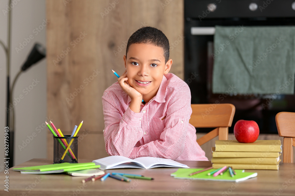 Little African-American boy doing homework in kitchen