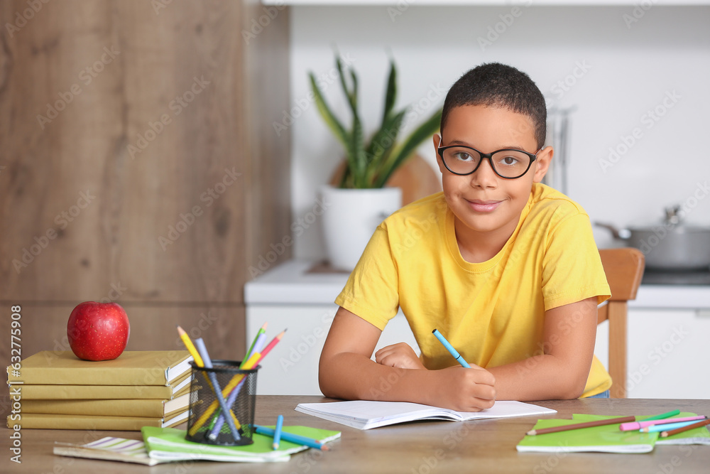 Little African-American boy doing homework in kitchen