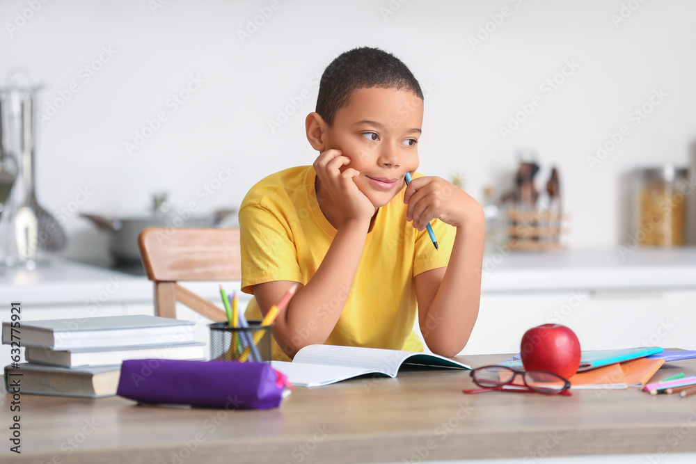 Little African-American boy doing homework in kitchen