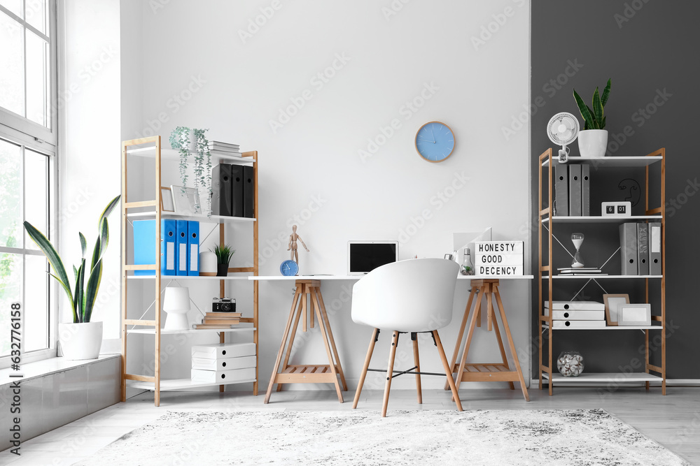 Interior of light office with modern workplace and shelving units