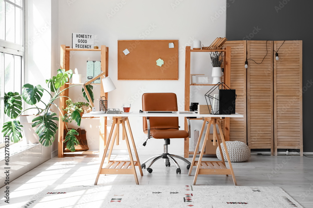 Interior of light office with workplace and shelving units