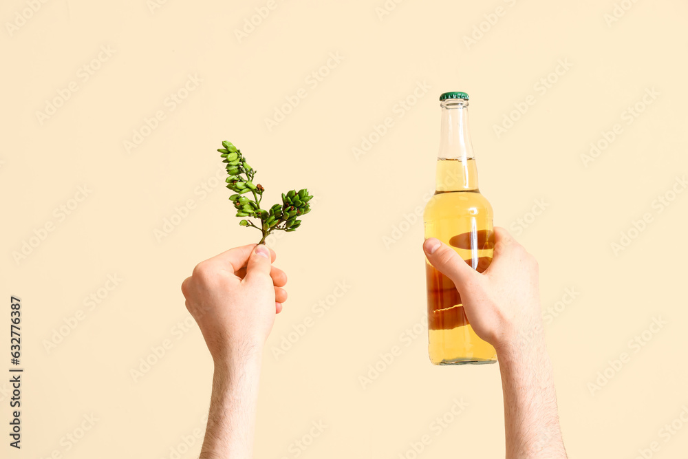 Man with bottle of beer and hop on beige background