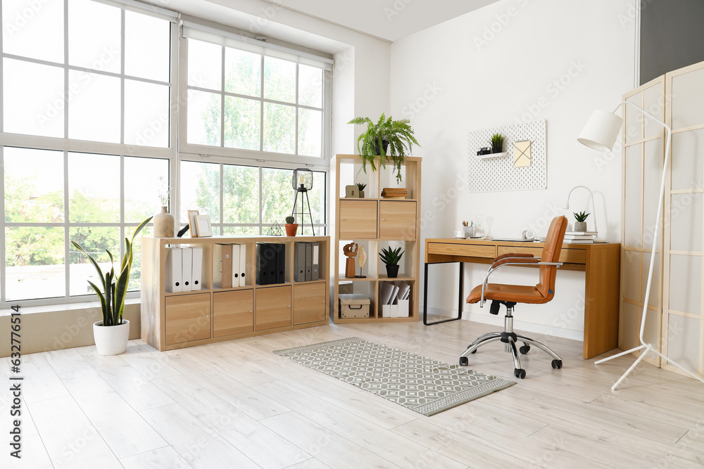 Interior of light office with modern workplace and shelving unit