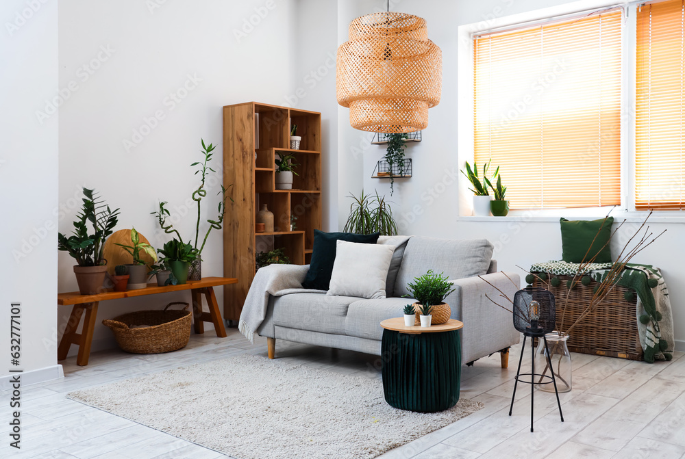 Interior of light living room with sofa and houseplants