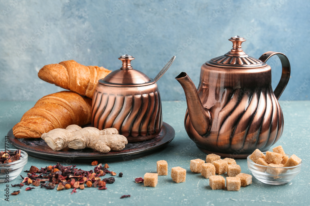 Composition with teapot, sugar and tasty croissants on color background