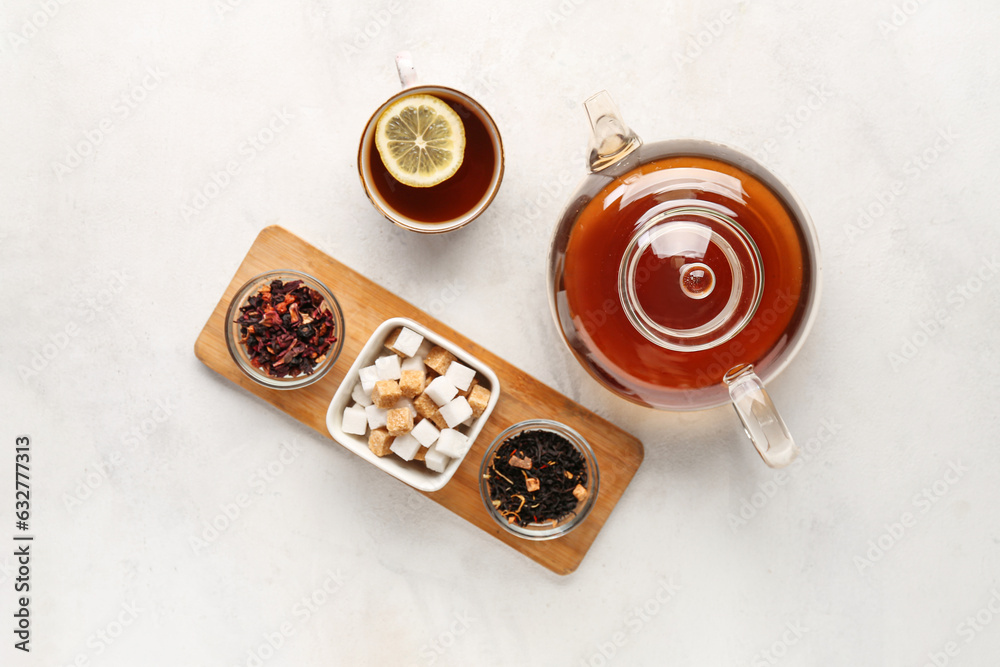 Cup of tea, teapot and sugar on light background