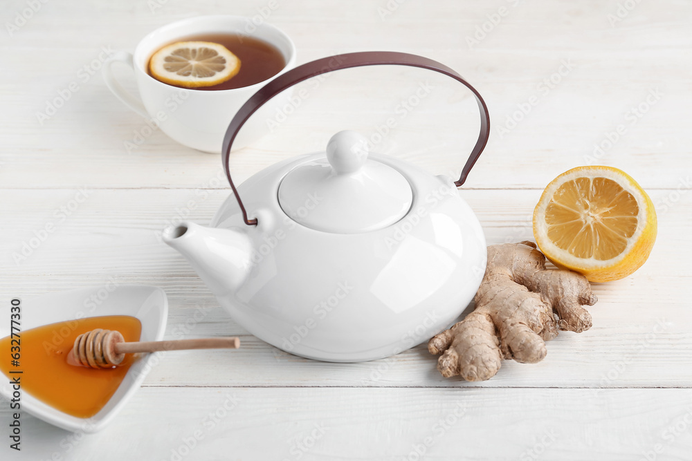 Teapot, cup of tea and ingredients on light wooden background