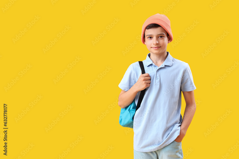 Portrait of schoolboy with backpack on orange background