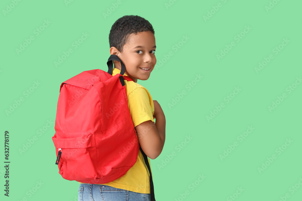 Little African-American boy with school backpack on green background