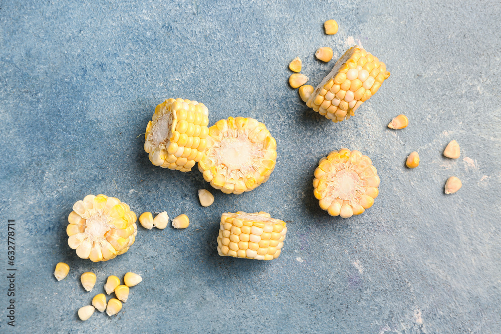 Cut fresh corn cob and seeds on blue background