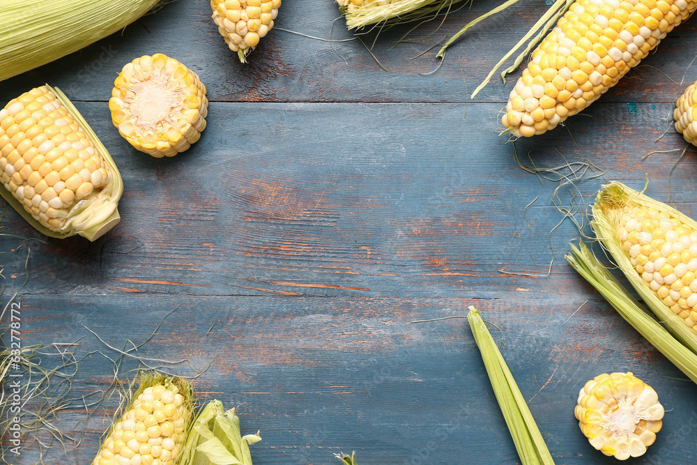 Frame made of fresh corn cobs on blue wooden background