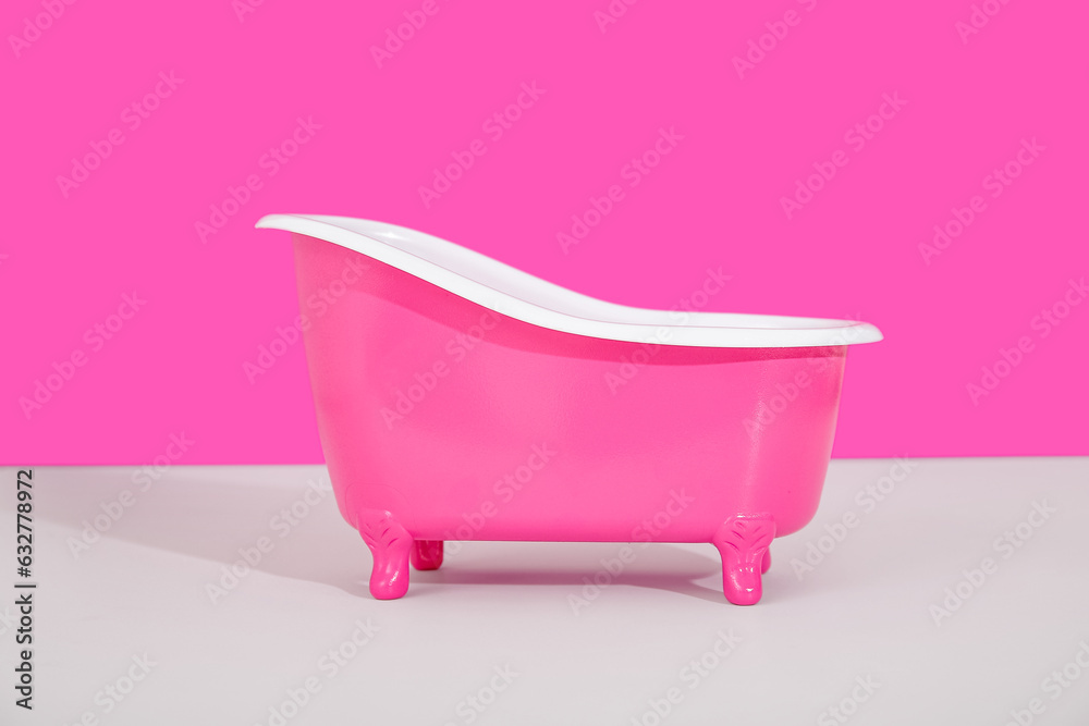 Small bathtub on light table against color background