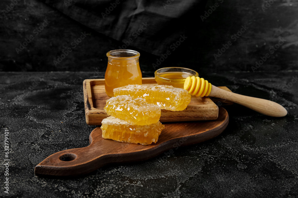 Wooden board with fresh honey and combs on dark background