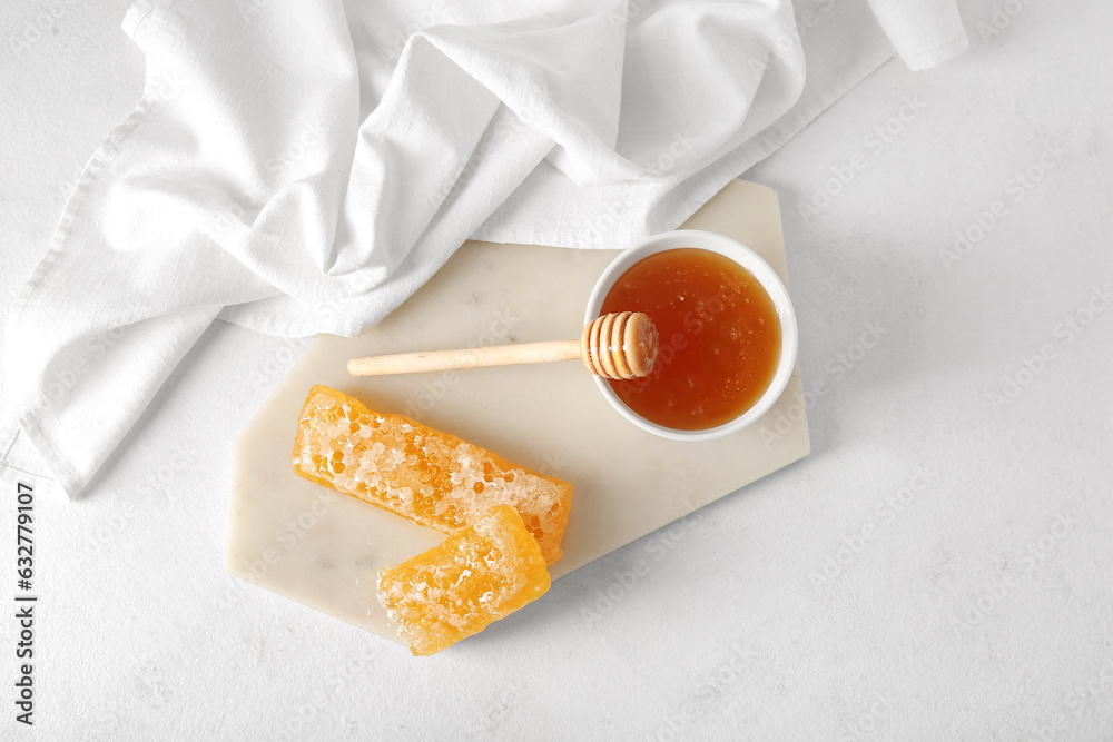 Board with bowl of sweet honey and combs on light background