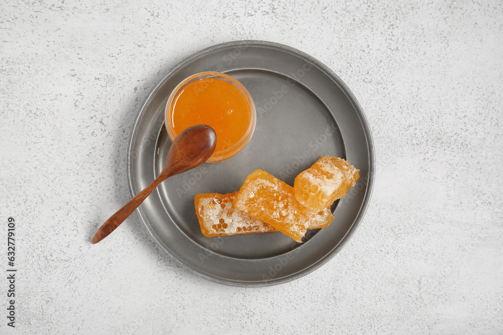 Plate with jar of sweet honey and combs on light background