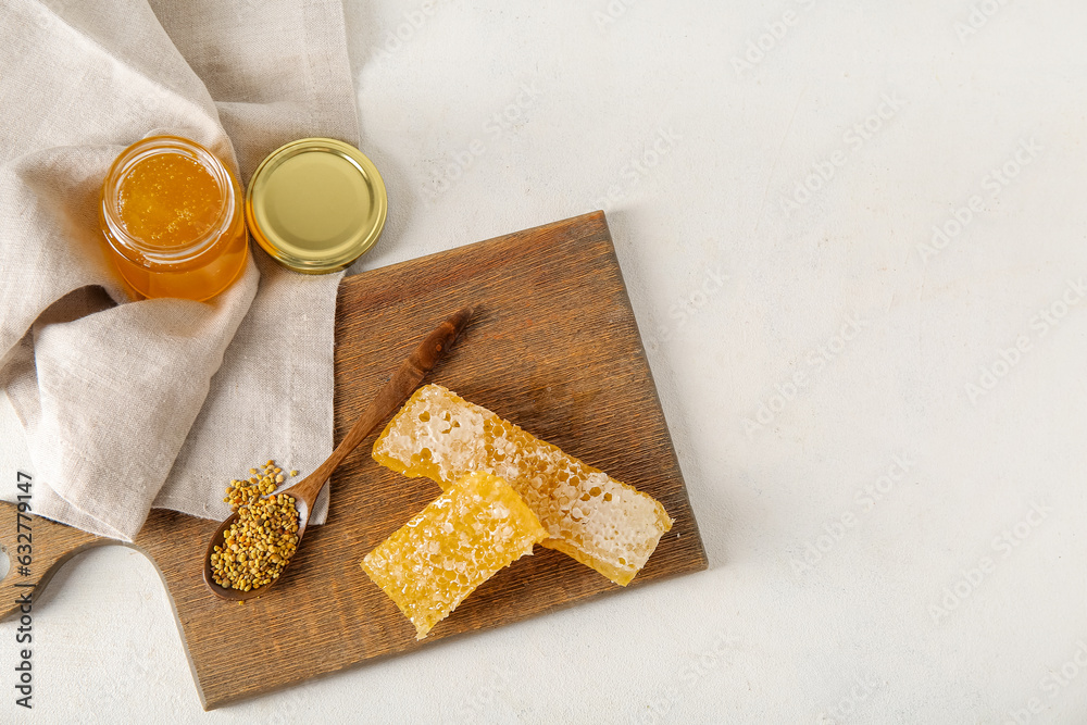 Jar of delicious honey, combs and bee pollen on light background