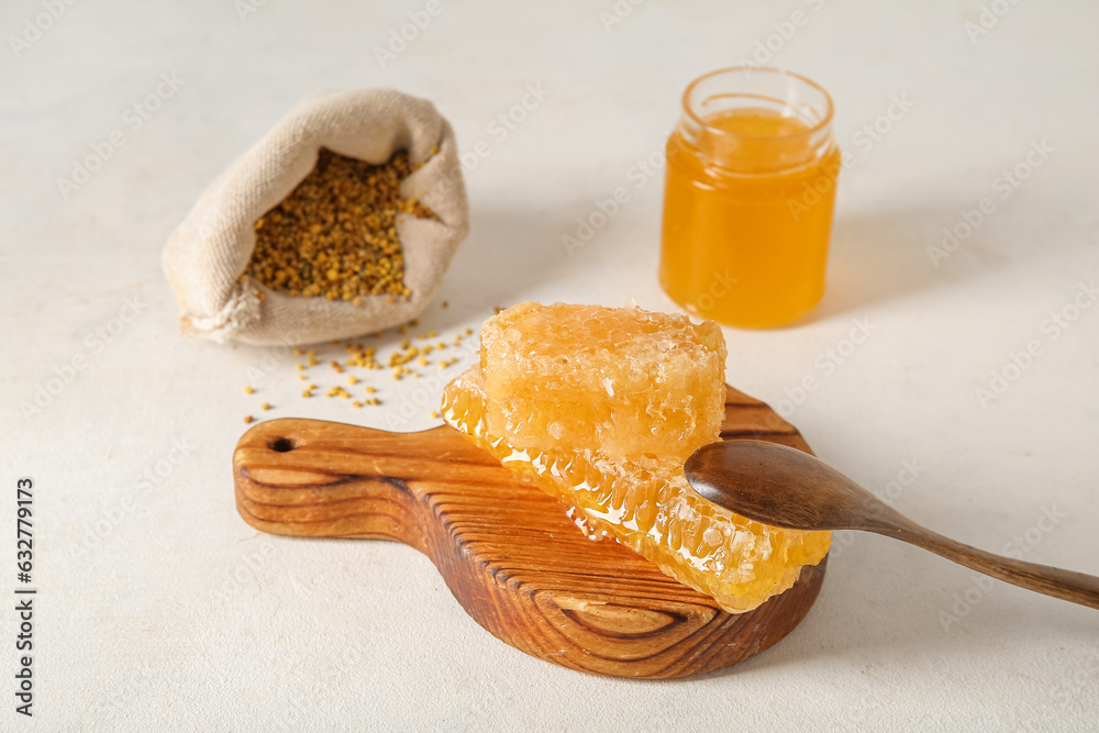 Jar of tasty honey, combs and bee pollen on light background