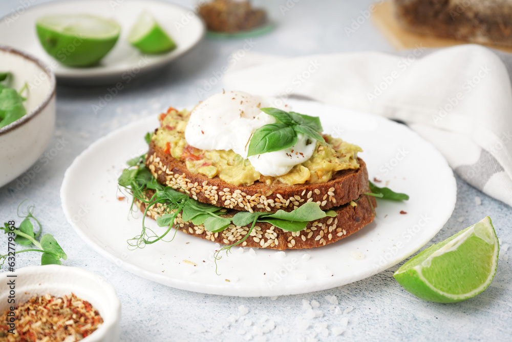 Plate of tasty sandwich with egg on grey background