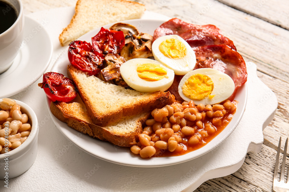 Plate of tasty English breakfast with boiled eggs on light wooden background