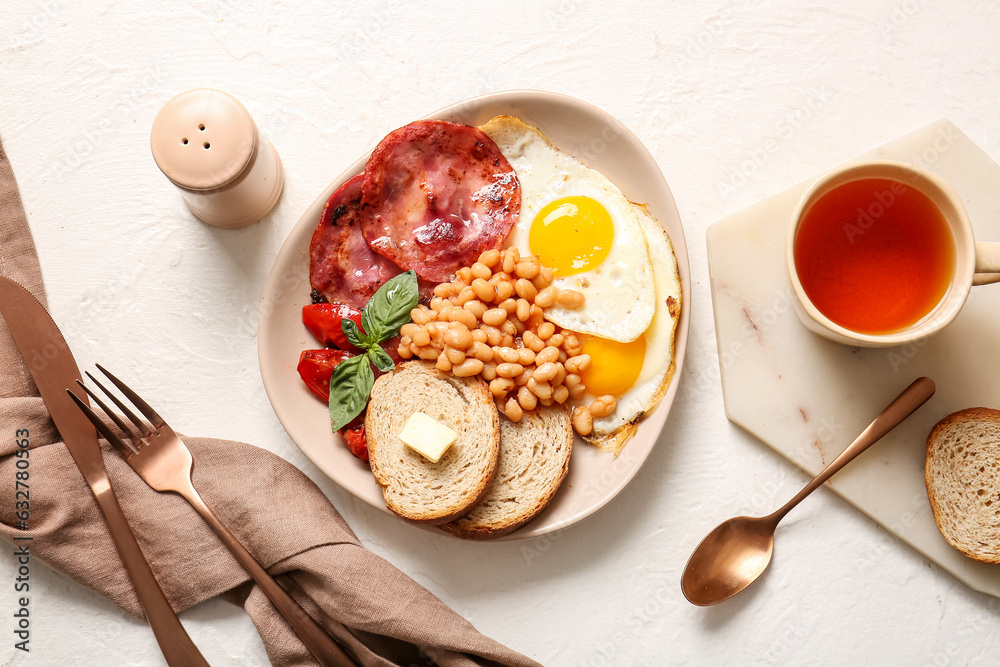 Plate with tasty English breakfast and cup of tea on white background