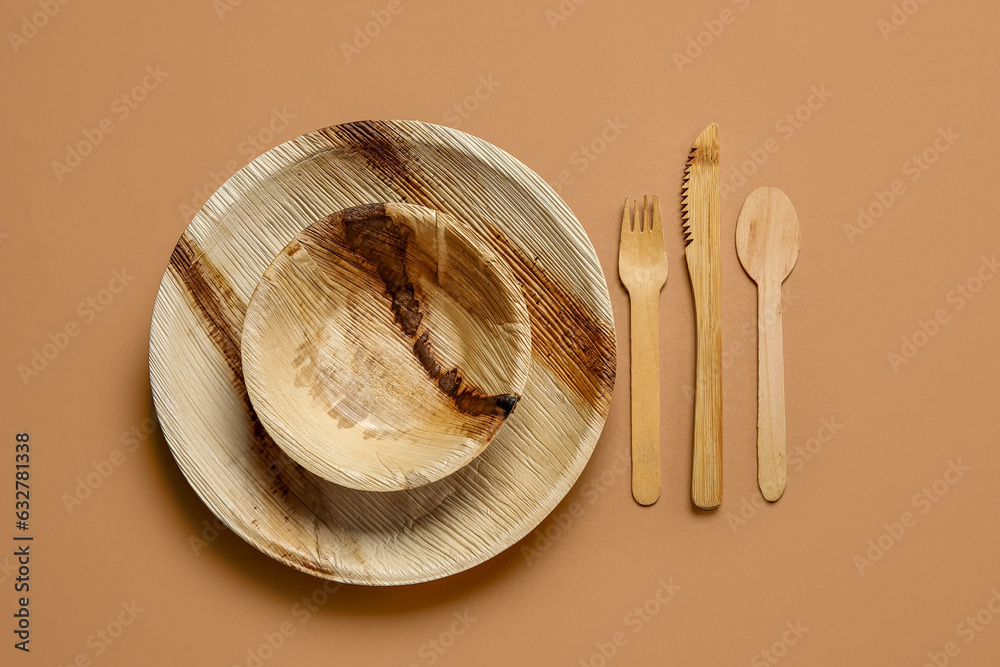 Wooden cutlery with plate and bowl on brown background