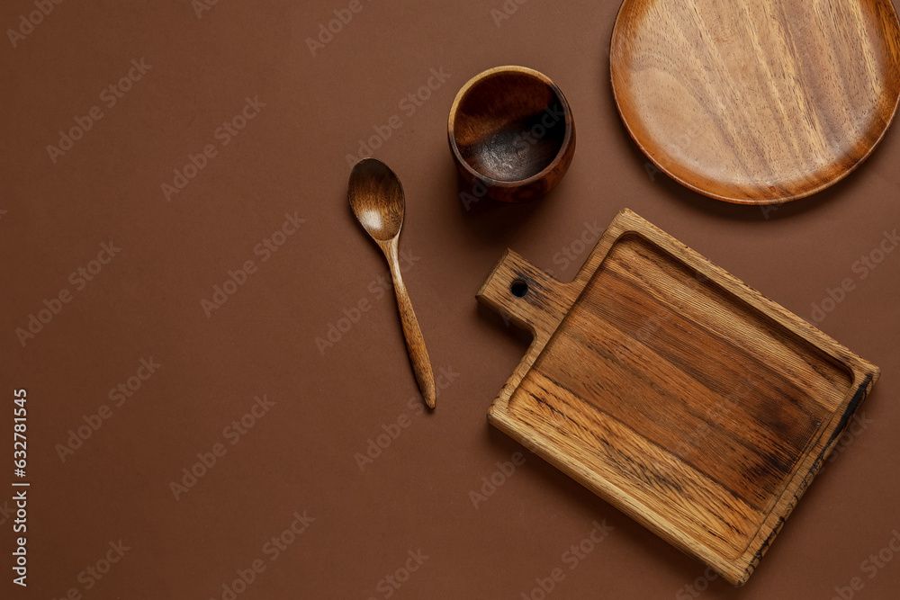 Different wooden tableware on brown background