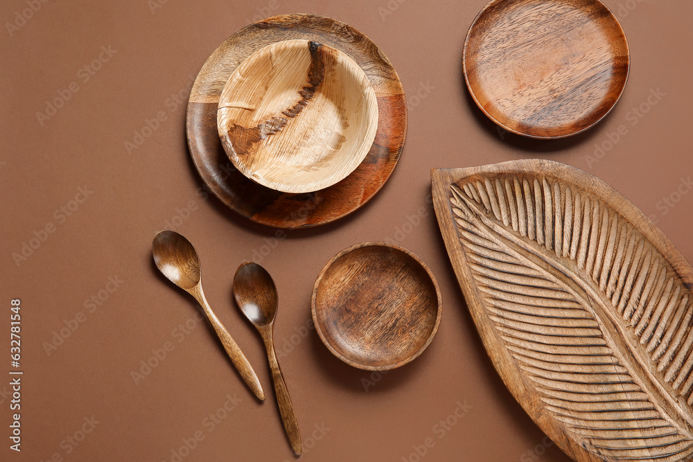 Different wooden tableware on brown background