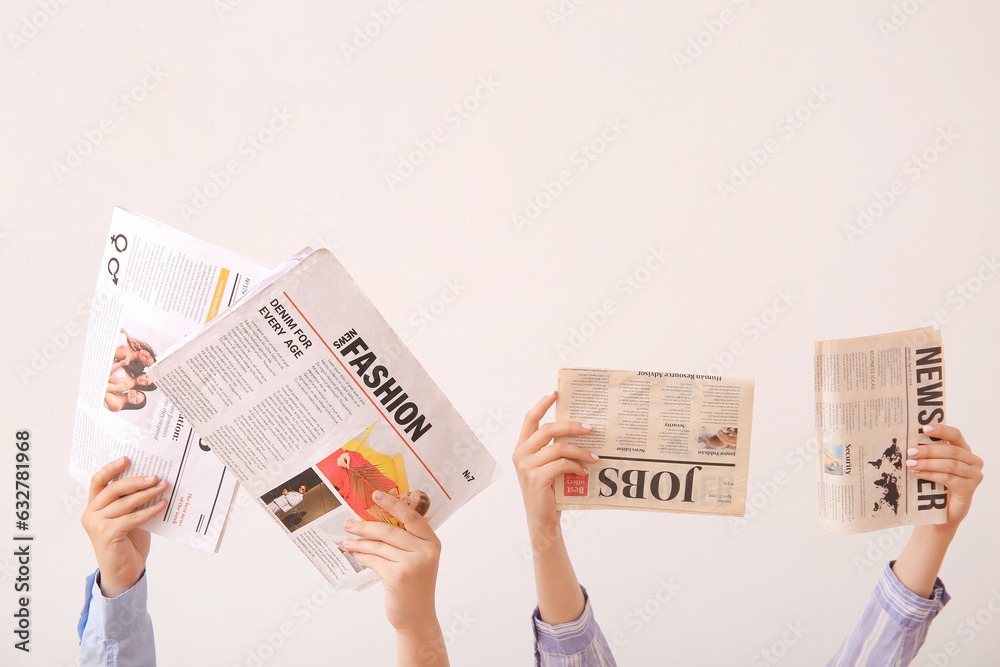 Female hands with different newspapers on light background