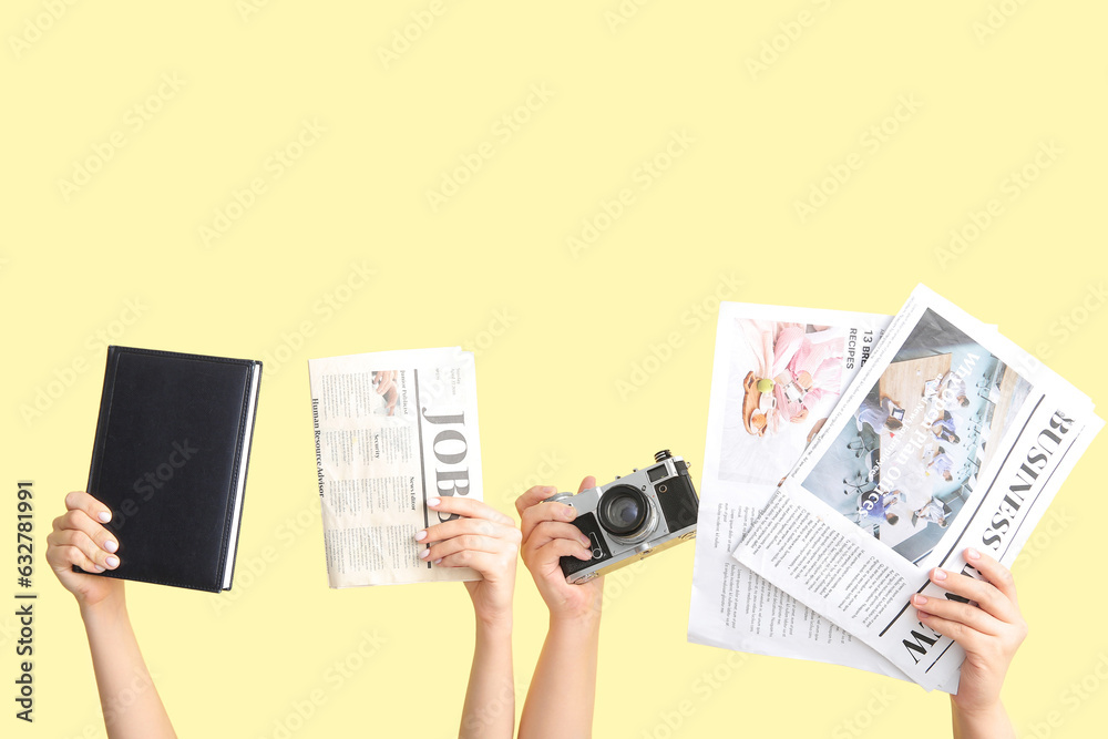 Female hands with notebook, photo camera and newspapers on color background