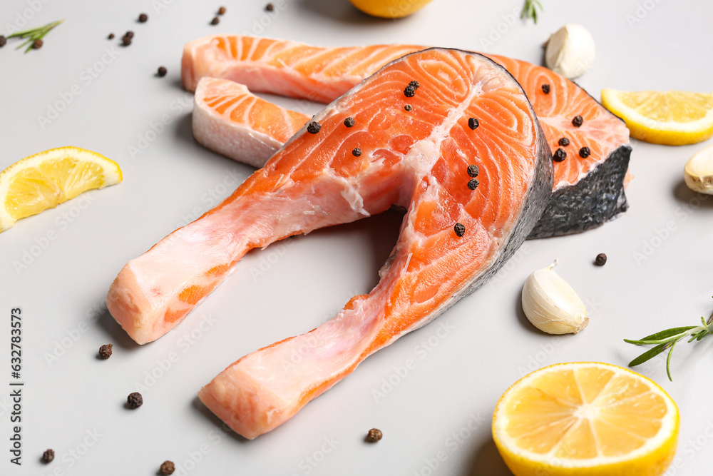 Raw salmon steaks and different spices on grey background