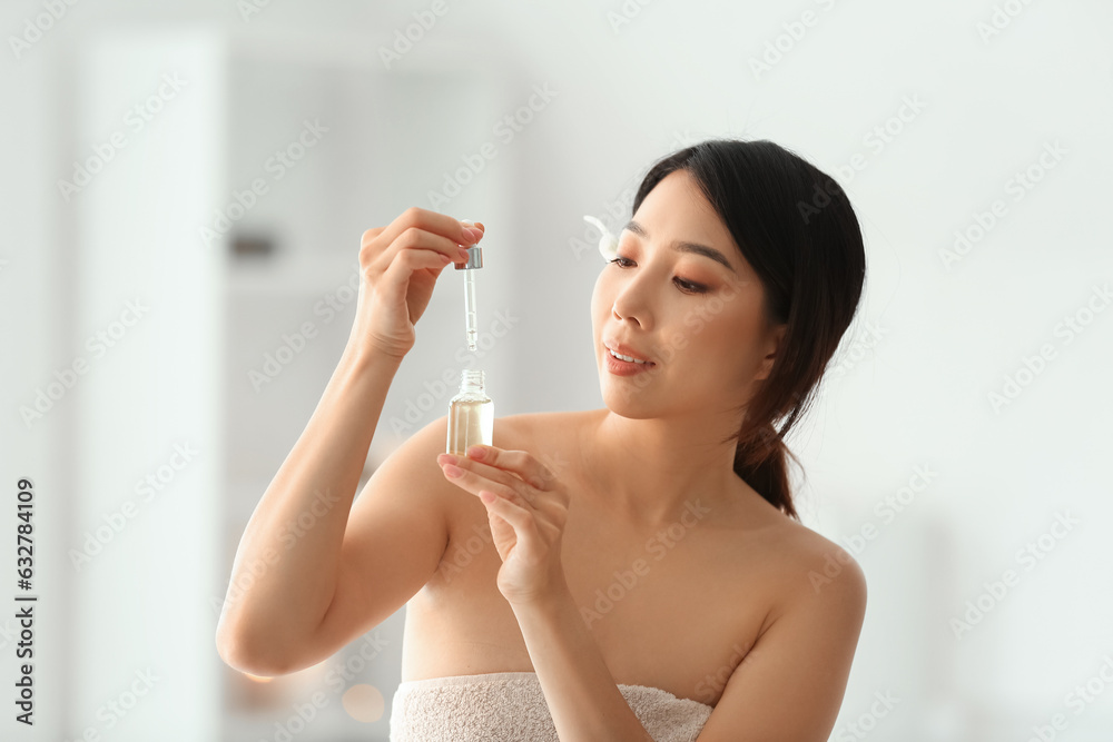 Pretty young Asian woman with essential oil in spa salon