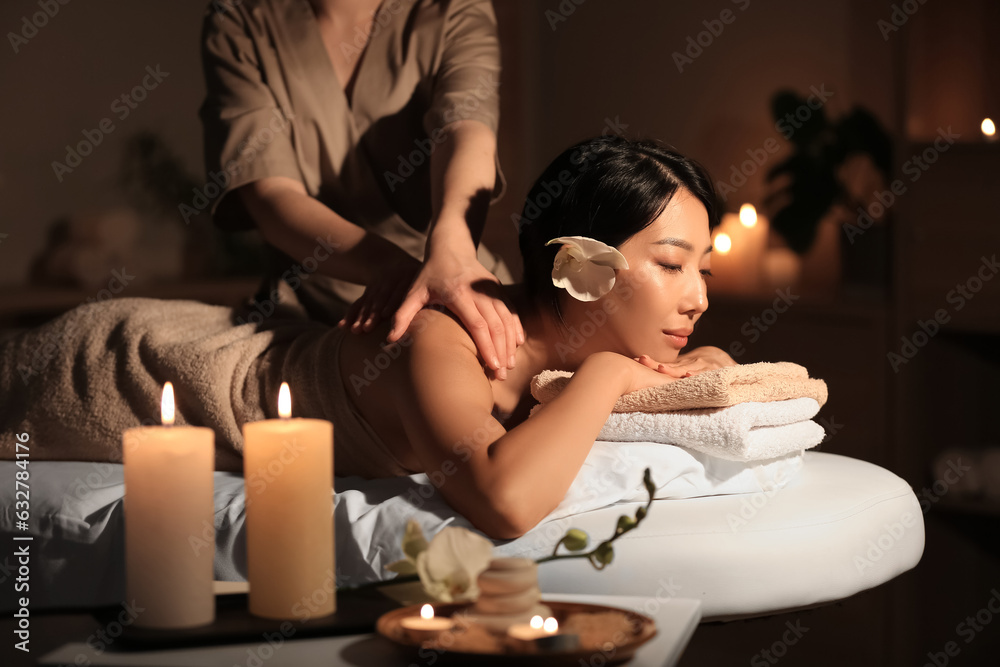 Pretty young Asian woman having massage in spa salon