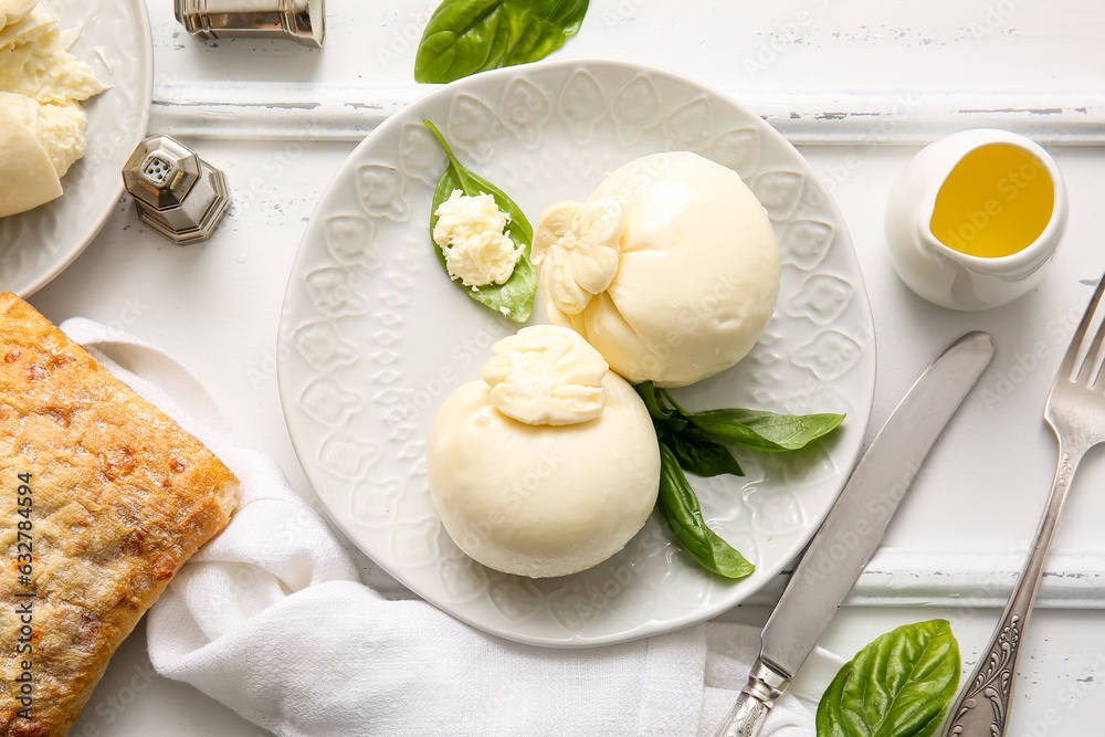 Plate of tasty Burrata cheese with basil and bread on white background