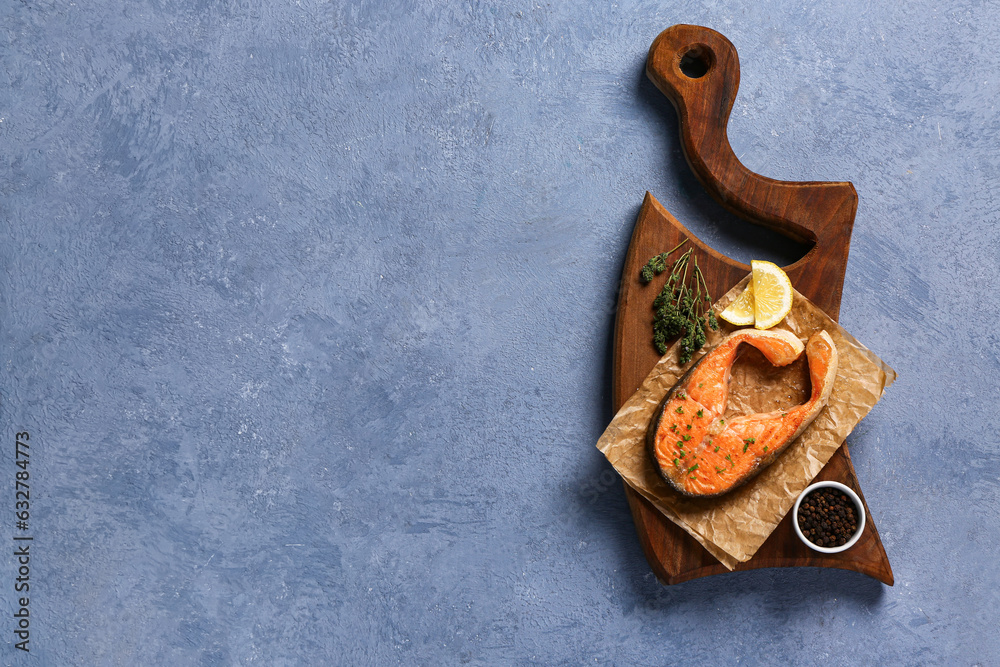 Wooden board of tasty salmon steak with lemon on blue background