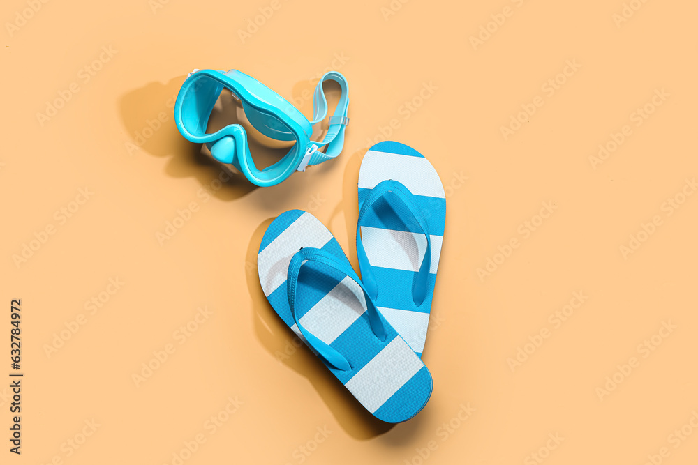 Female stylish flip flops with snorkeling mask on orange background