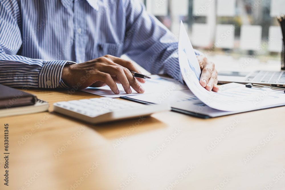 Businessman working with laptop and analyzing charts on financial documents with calculator.