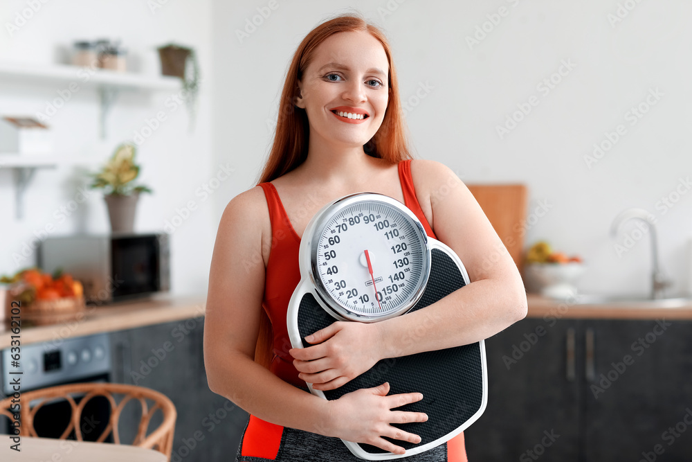 Young overweight woman with scales in kitchen