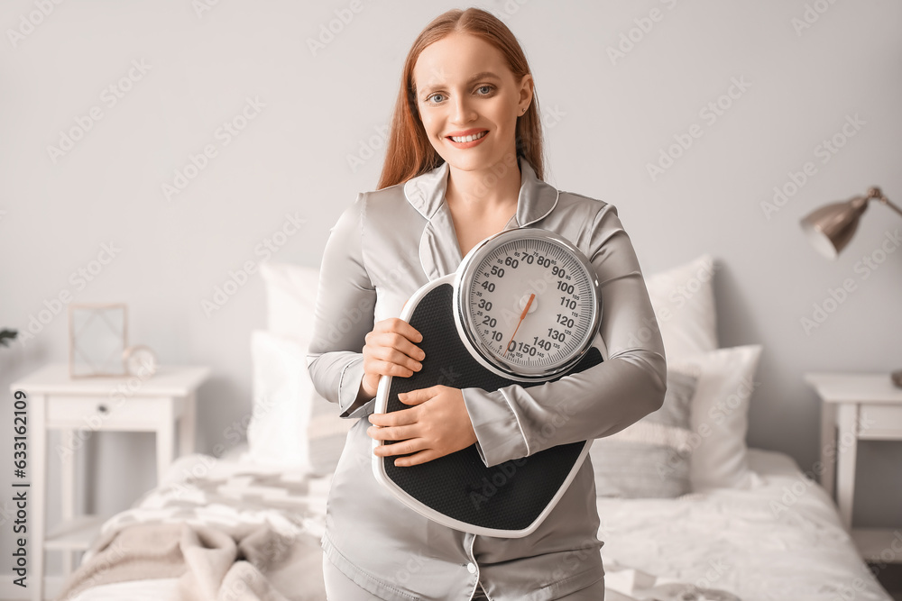 Young overweight woman with scales in bedroom