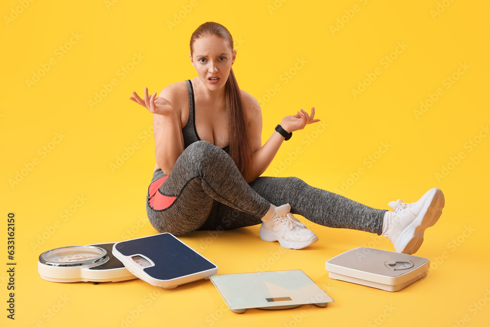 Upset young overweight woman with scales on yellow background