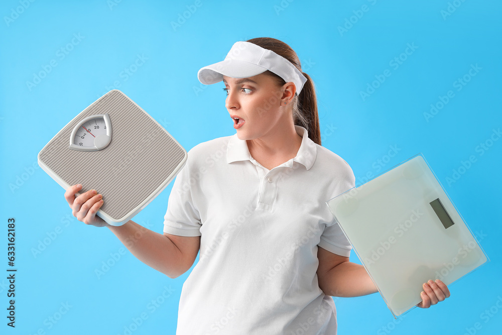 Worried young overweight woman with scales on blue background