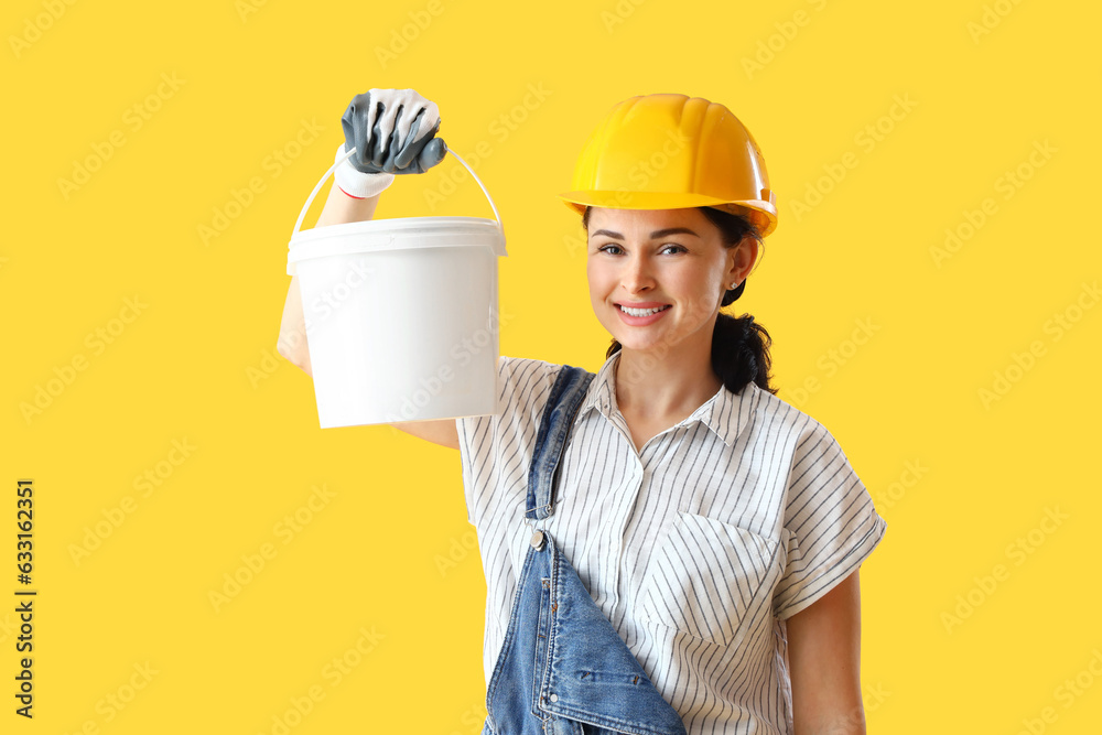 Female decorator with bucket of paint on yellow background