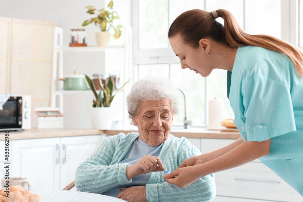 Female caregiver giving pills to senior woman in kitchen