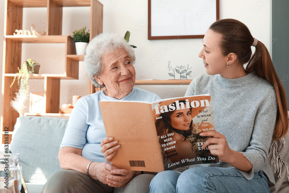 Senior woman with her granddaughter reading magazine at home