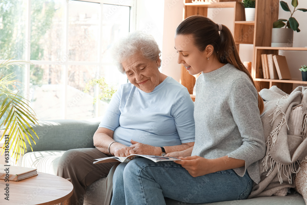 Senior woman with her granddaughter reading magazine at home