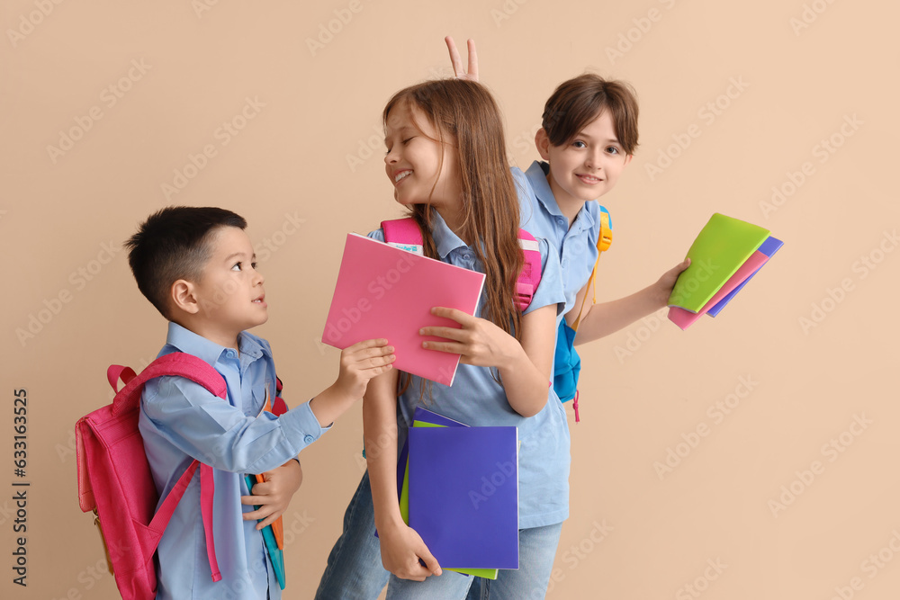 Little pupils with copybooks on beige background