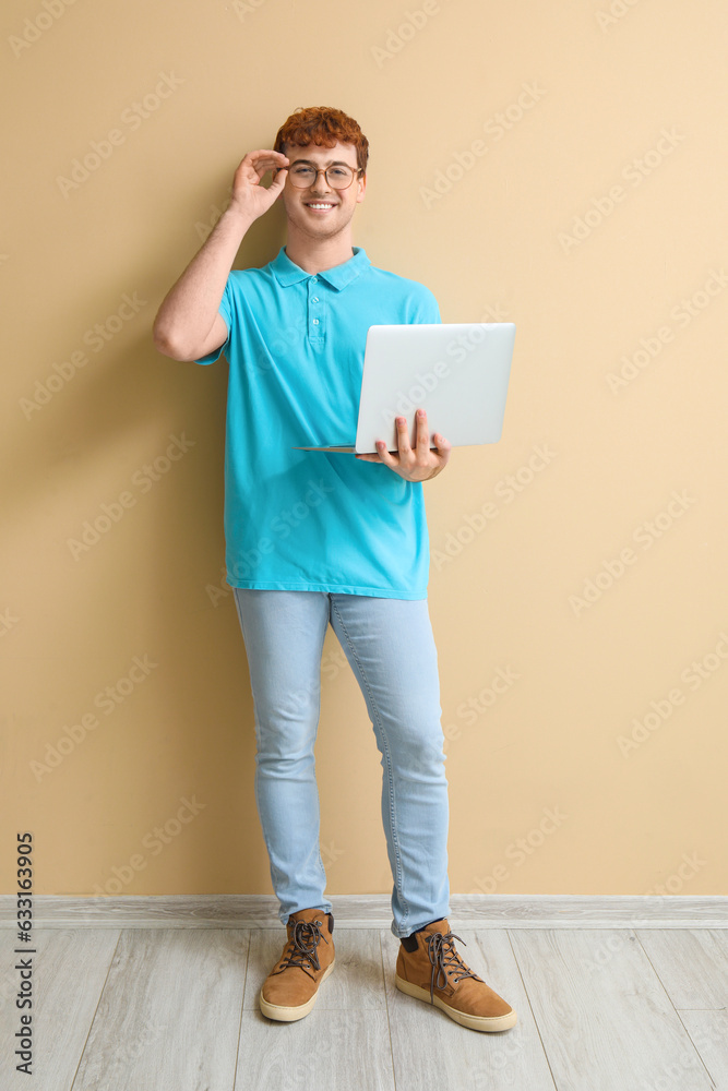 Male programmer working with laptop near beige wall