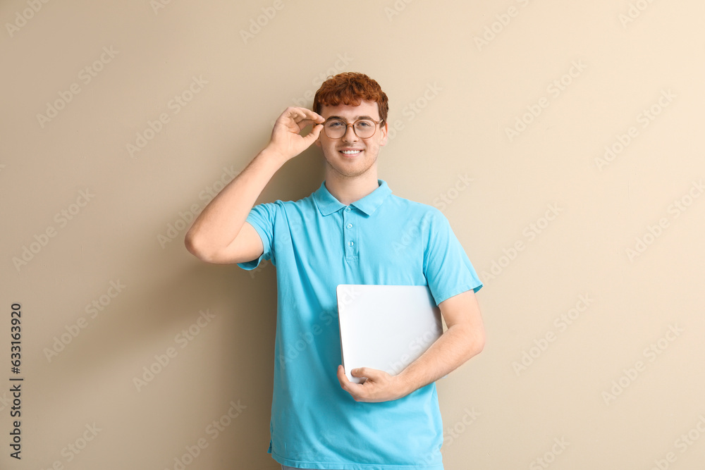 Male programmer with laptop on beige background